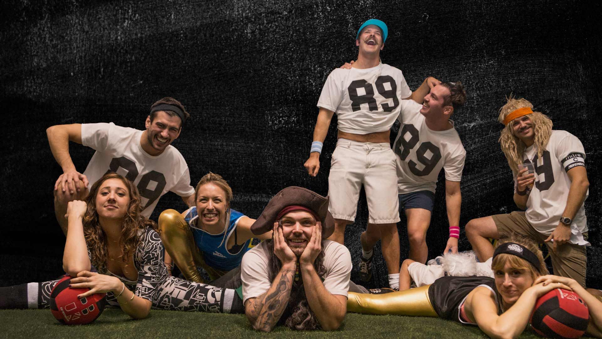 Stylised photo of a group of jolly-looking friends. Some wear a mix of numbered sporting attire.