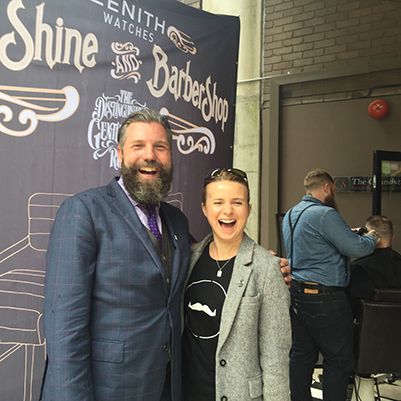 Photo of two people smiling to camera inside a barber shop.